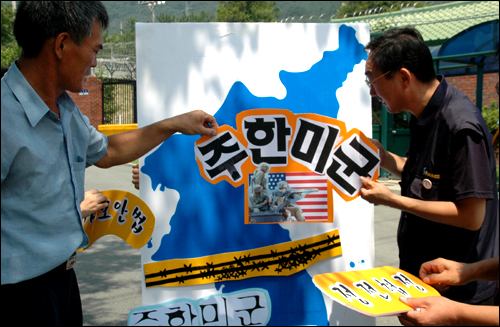 경남진보연합 대표들이 미군사고문단 앞에서 한반도를 그려 놓고 '정전협정'을 뜯어내는 퍼포먼스를 하고 있다. 